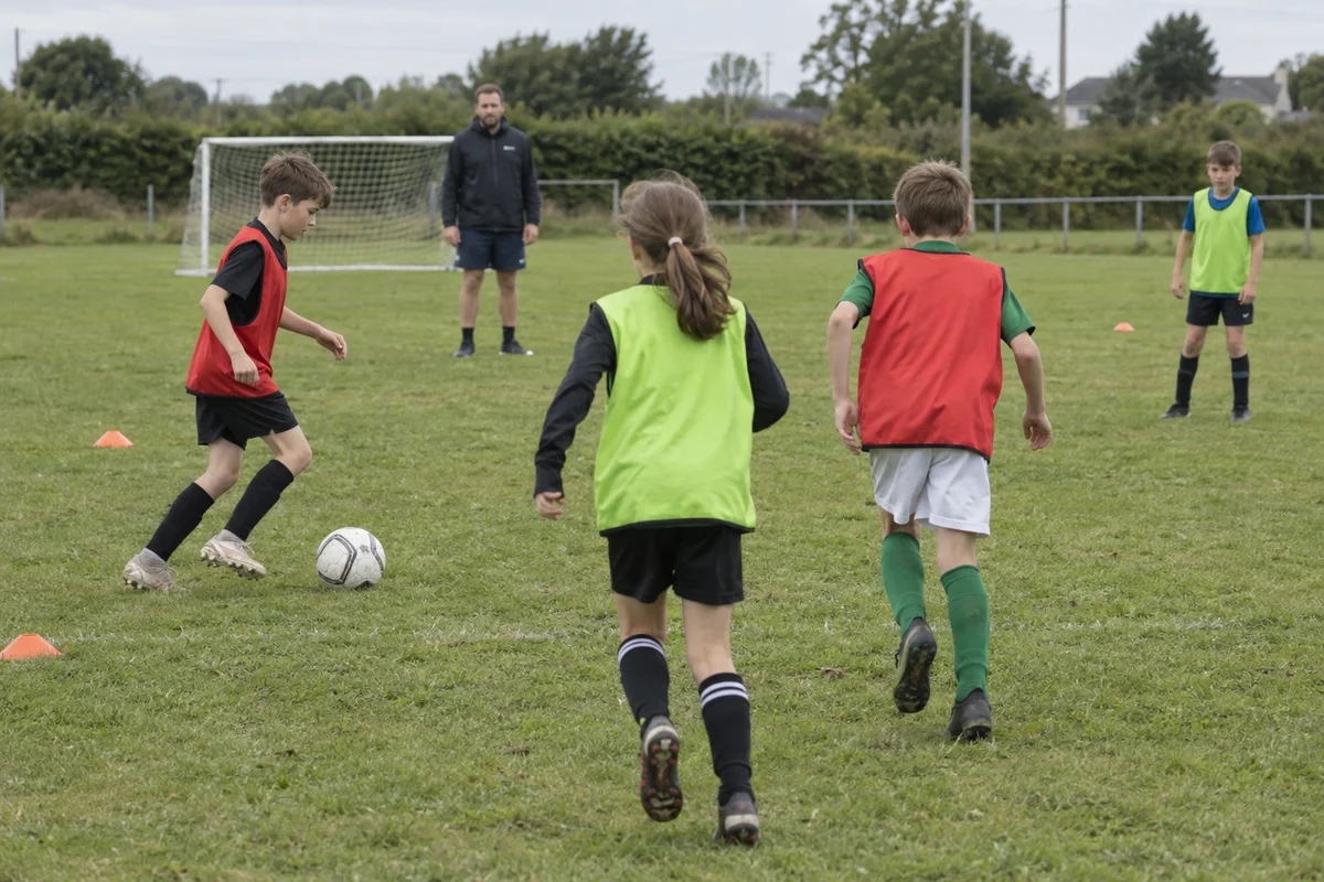 Children playing football together at an outdoor camp